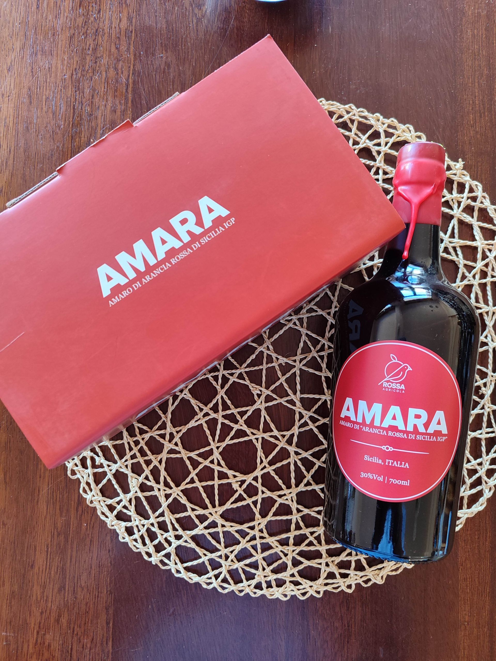 Confezione regalo Amara e bottiglia su una stuoia intrecciata, con uno sfondo in legno