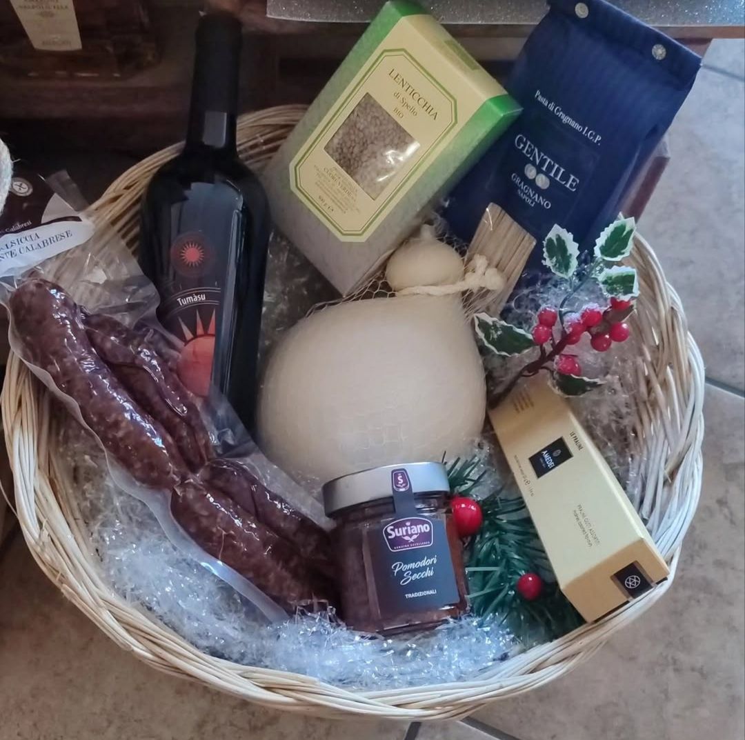 Cesto regalo con vino, snack, sapone e dolcetti in un vassoio di vimini