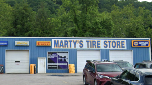 Marty’s Tire Store storefront with blue siding, garage bays, and parked cars in front