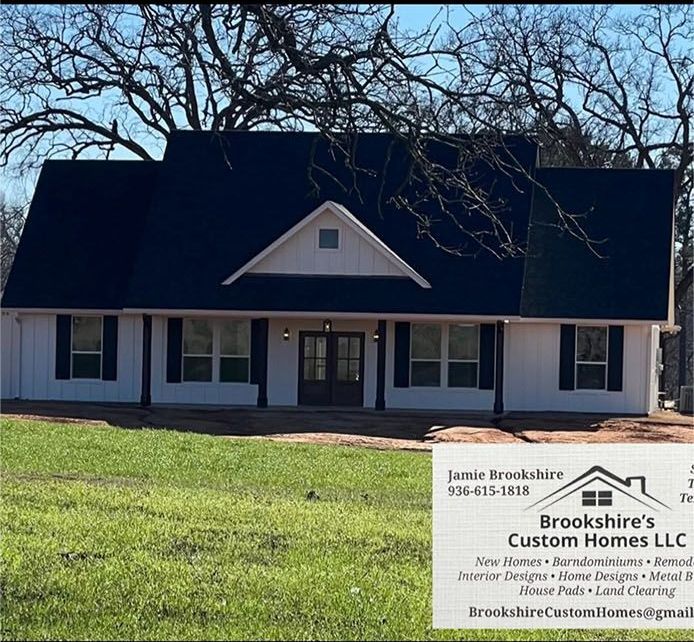 Brooks Homes LLC sign in front of a white house with dark roof and bare trees