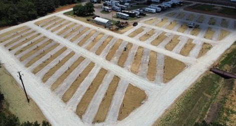 Aerial view of a construction site with long rows of sandy foundations and gravel paths