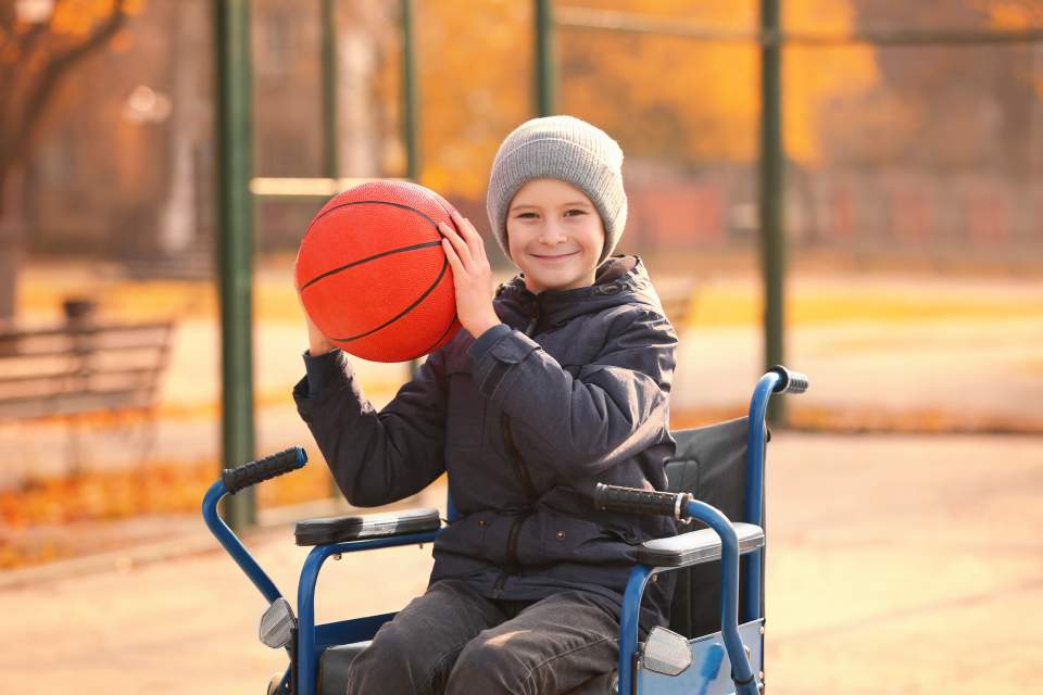 handicap boy on a wheelchair holding a basketball