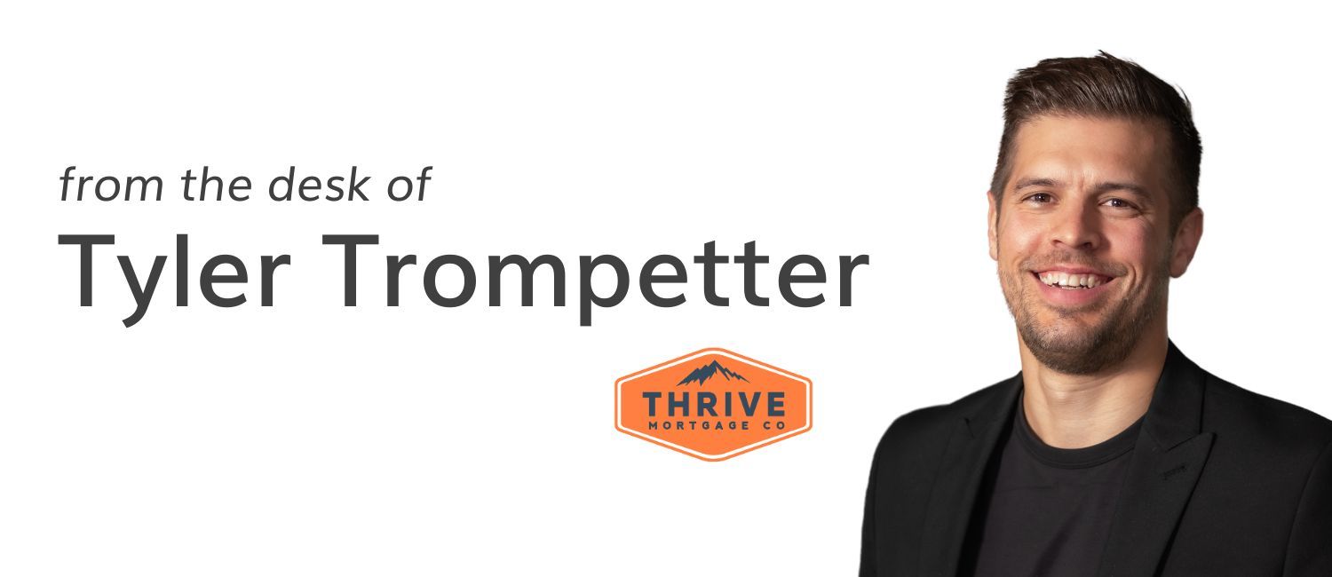A man is standing in front of a sign that says from the desk of tyler trumpetter.