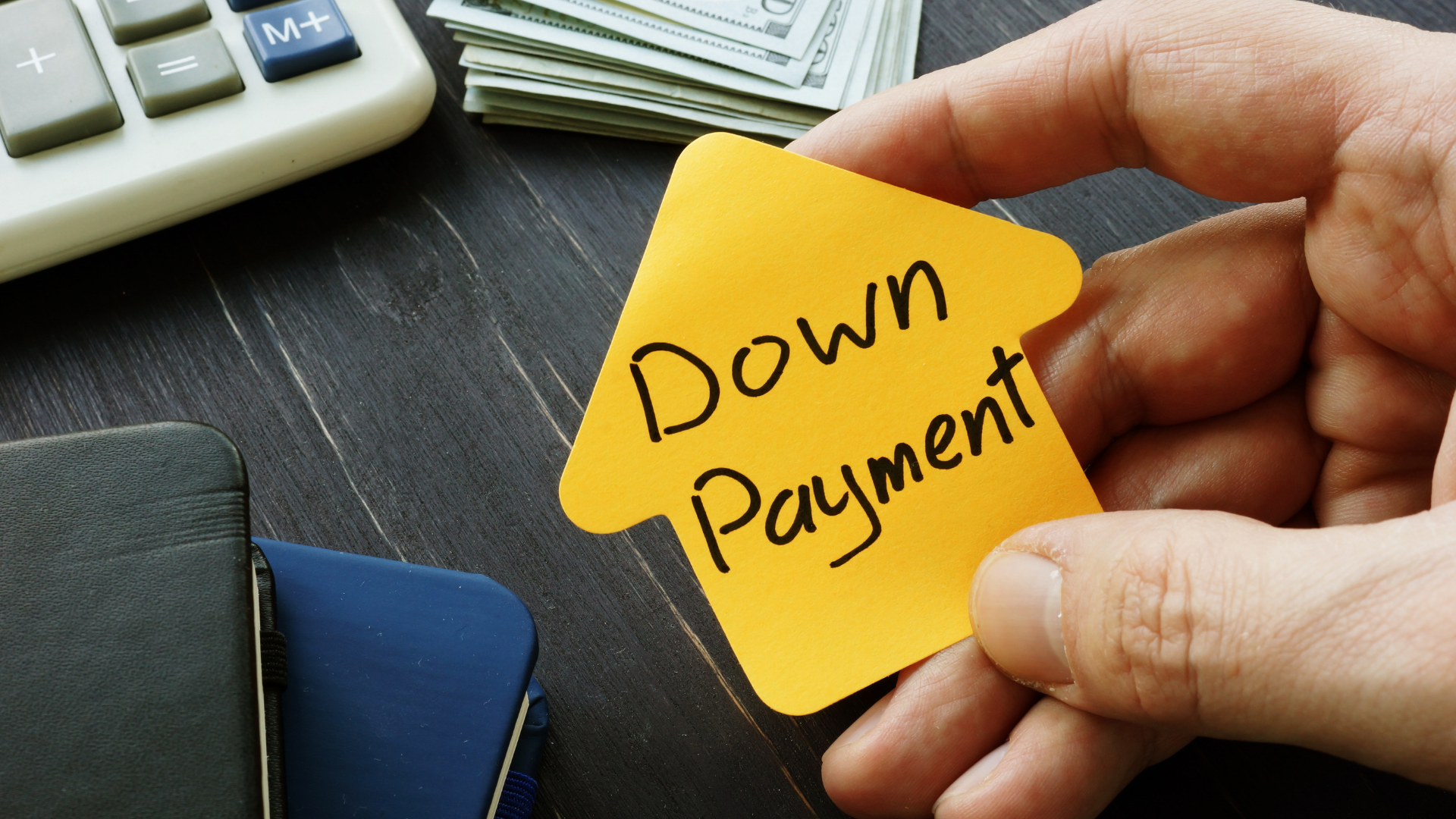 A person is holding a yellow sticky note that says down payment