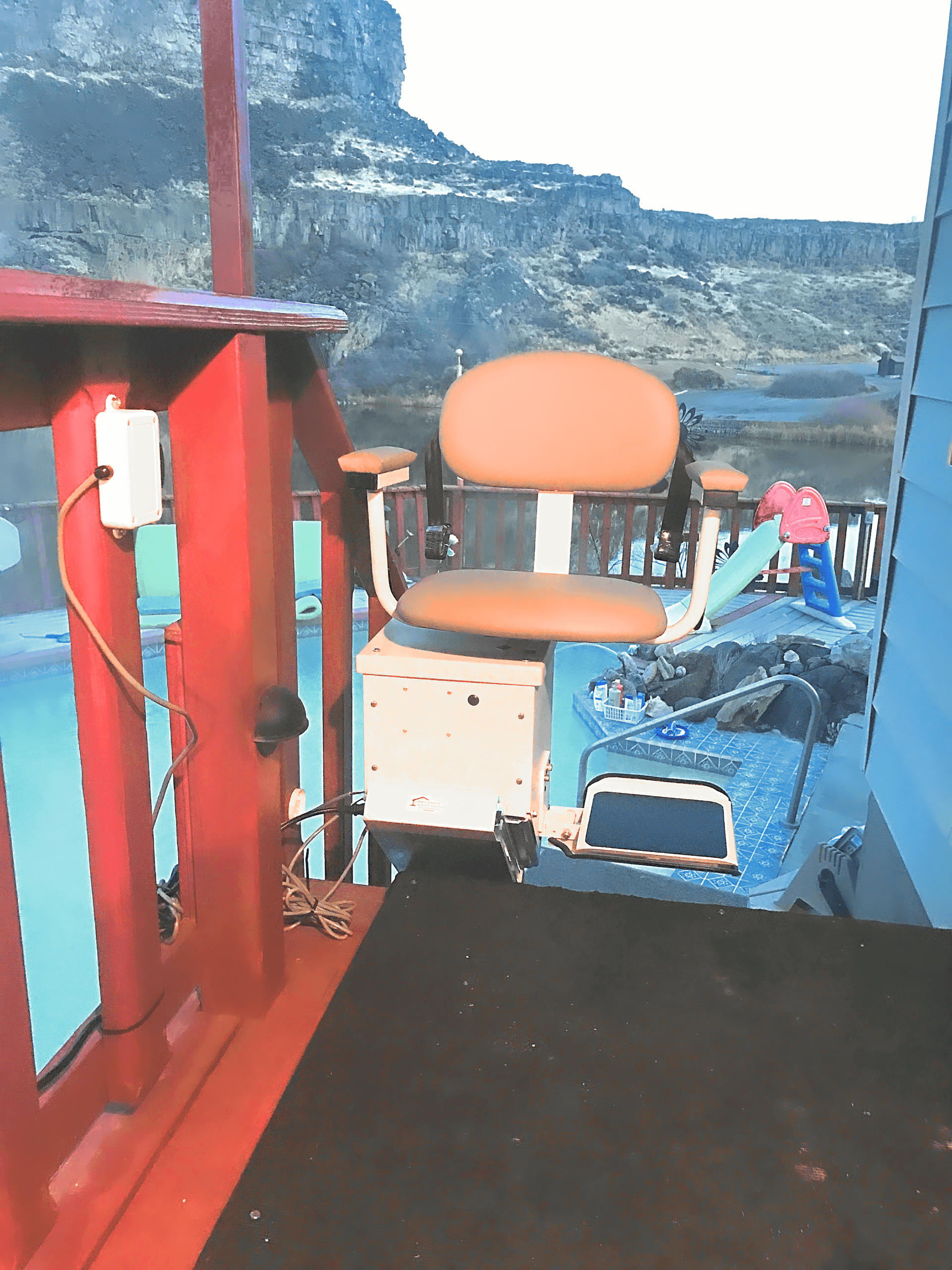 A chair on a balcony with a mountain in the background