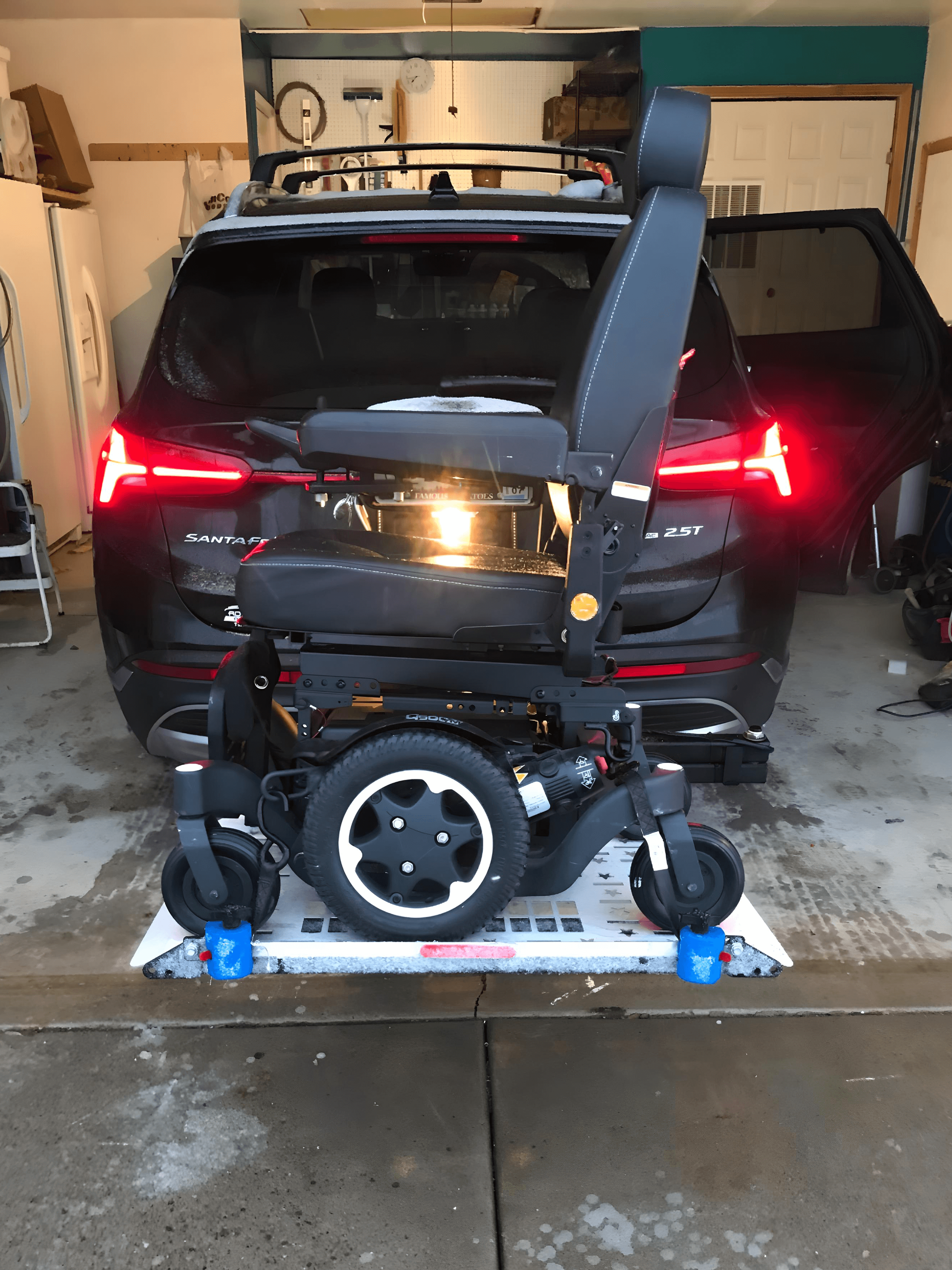 A wheelchair is attached to the back of a car in a garage.