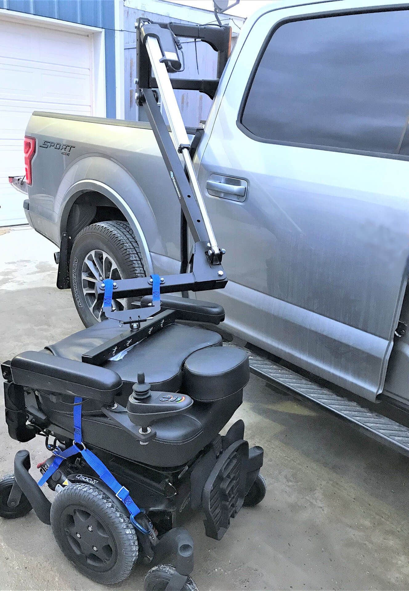 Power wheelchair next to a pickup truck with a mobility lift attached.