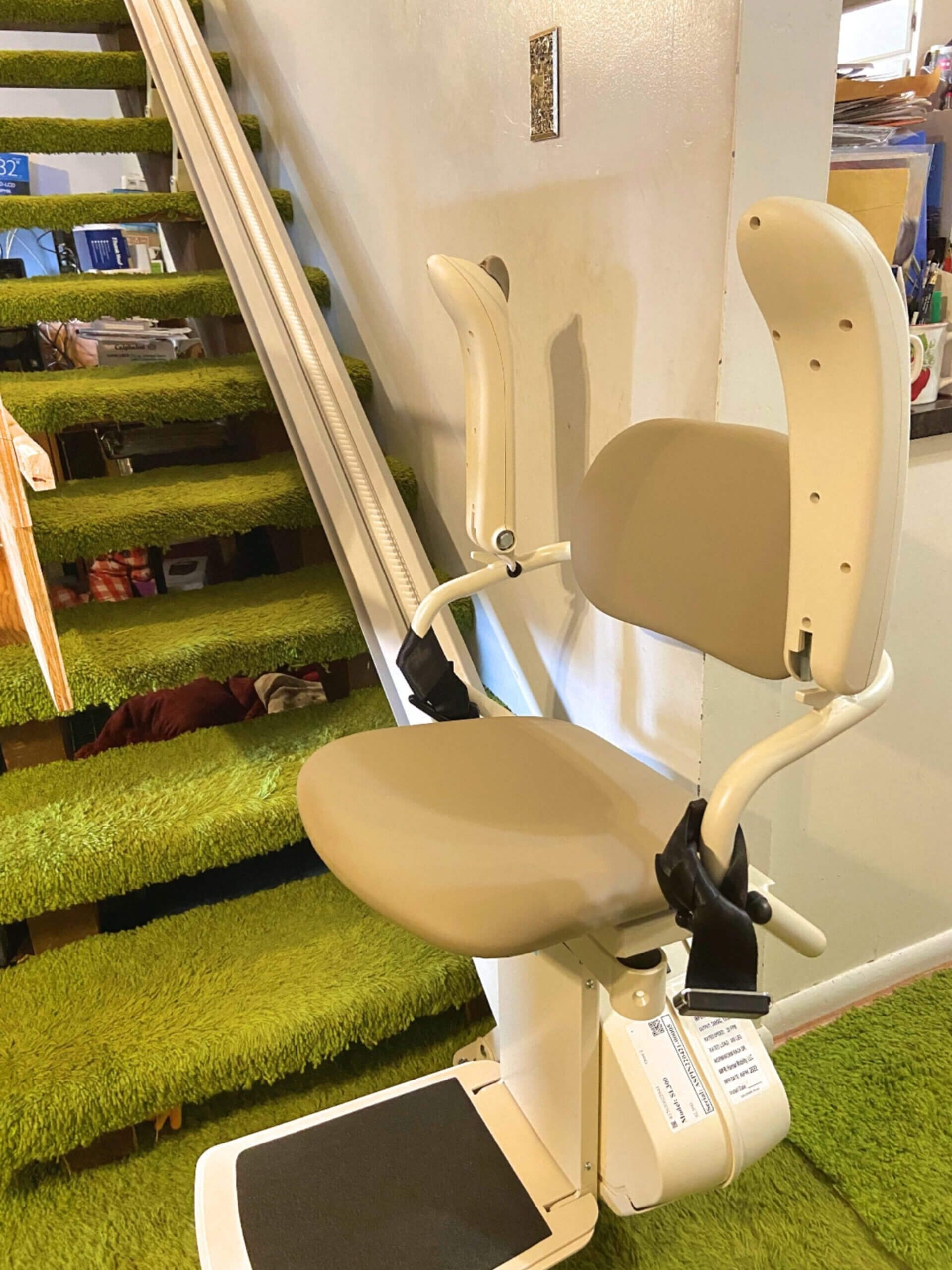A stair lift is sitting on top of a green carpeted staircase.