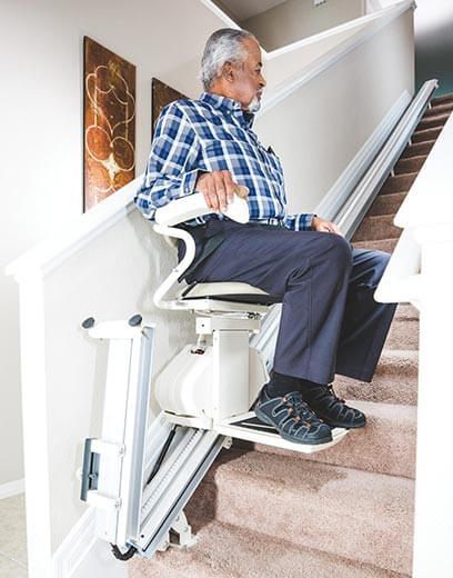 An elderly man is sitting on a stair lift