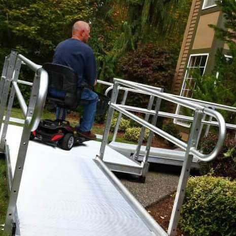 A man is sitting on a mobility scooter on a ramp.