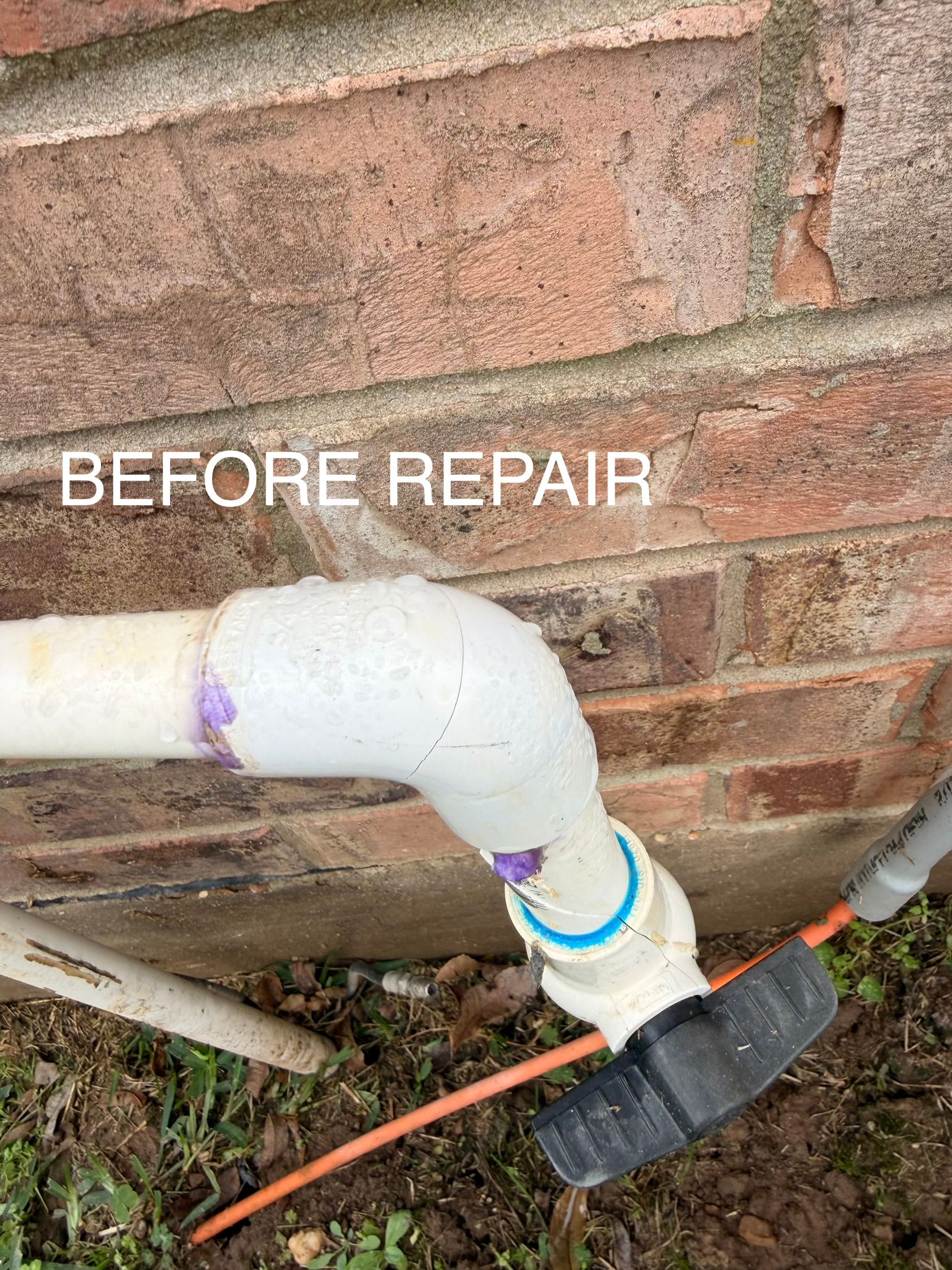 “Before repair” label on a white PVC pipe elbow and outdoor plumbing against a brick wall.