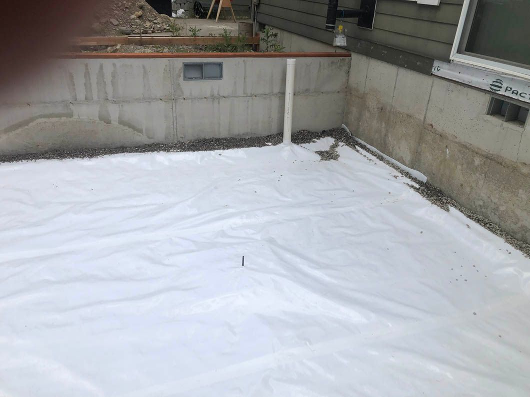 A White Tarp is Laying on the Ground Next to a Concrete Wall.