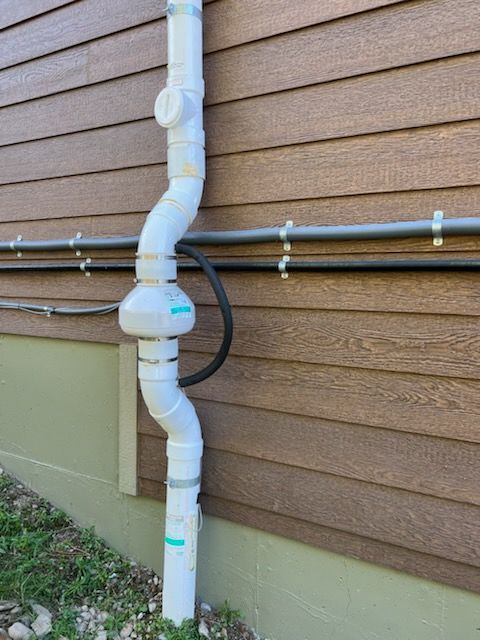 A white pipe is attached to the side of a house