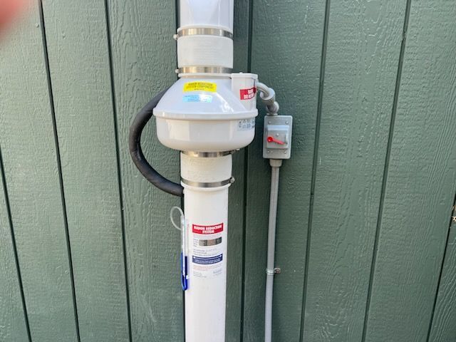 Concrete utility wall with white and turquoise pipes and a yellow level marker near the corner.
