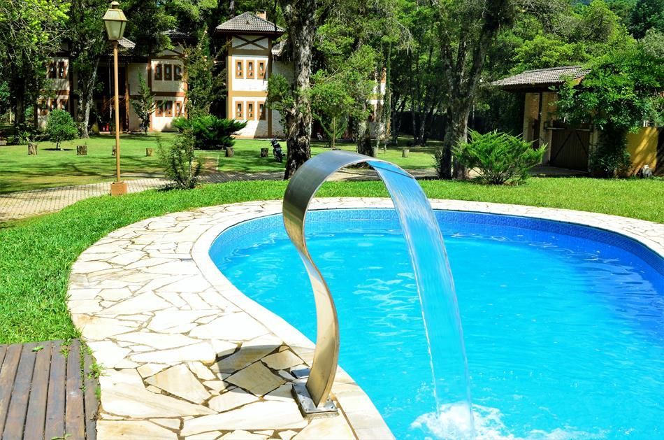 Piscina azul curva com fonte em arco em um jardim exuberante.