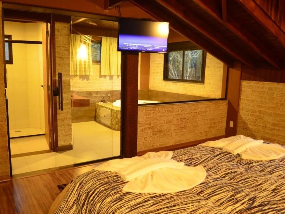 Pequeno quarto no sótão com duas camas de solteiro, teto inclinado e vista para um banheiro aconchegante com azulejos.