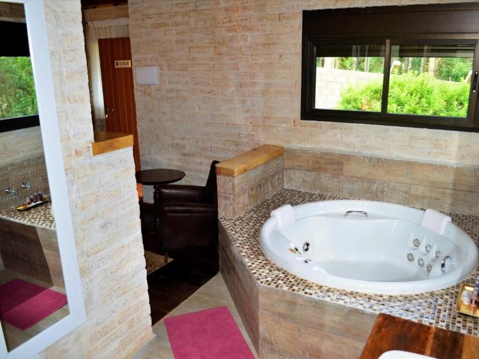 Banheiro moderno com spa, banheira de hidromassagem branca embutida, azulejos em mosaico e janela com vista para o exterior.