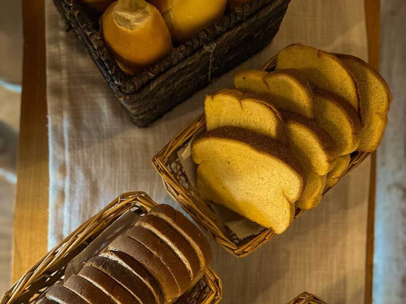Cestas de pão fatiado e pãezinhos sobre uma mesa de madeira