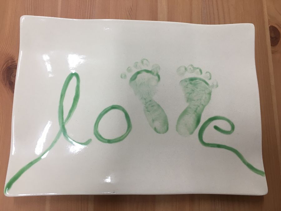 Ein weißer Teller mit grünen Fußabdrücken und dem Wort Liebe darauf geschrieben