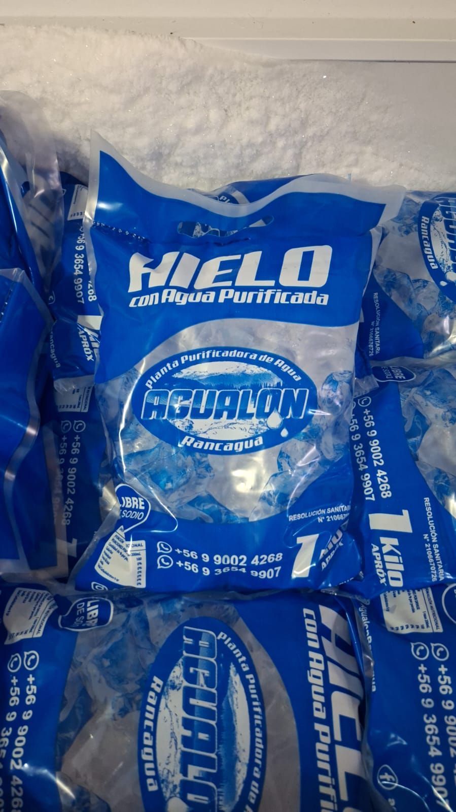 Bolsas de hielo azules de la marca HEB apiladas en un compartimento del congelador