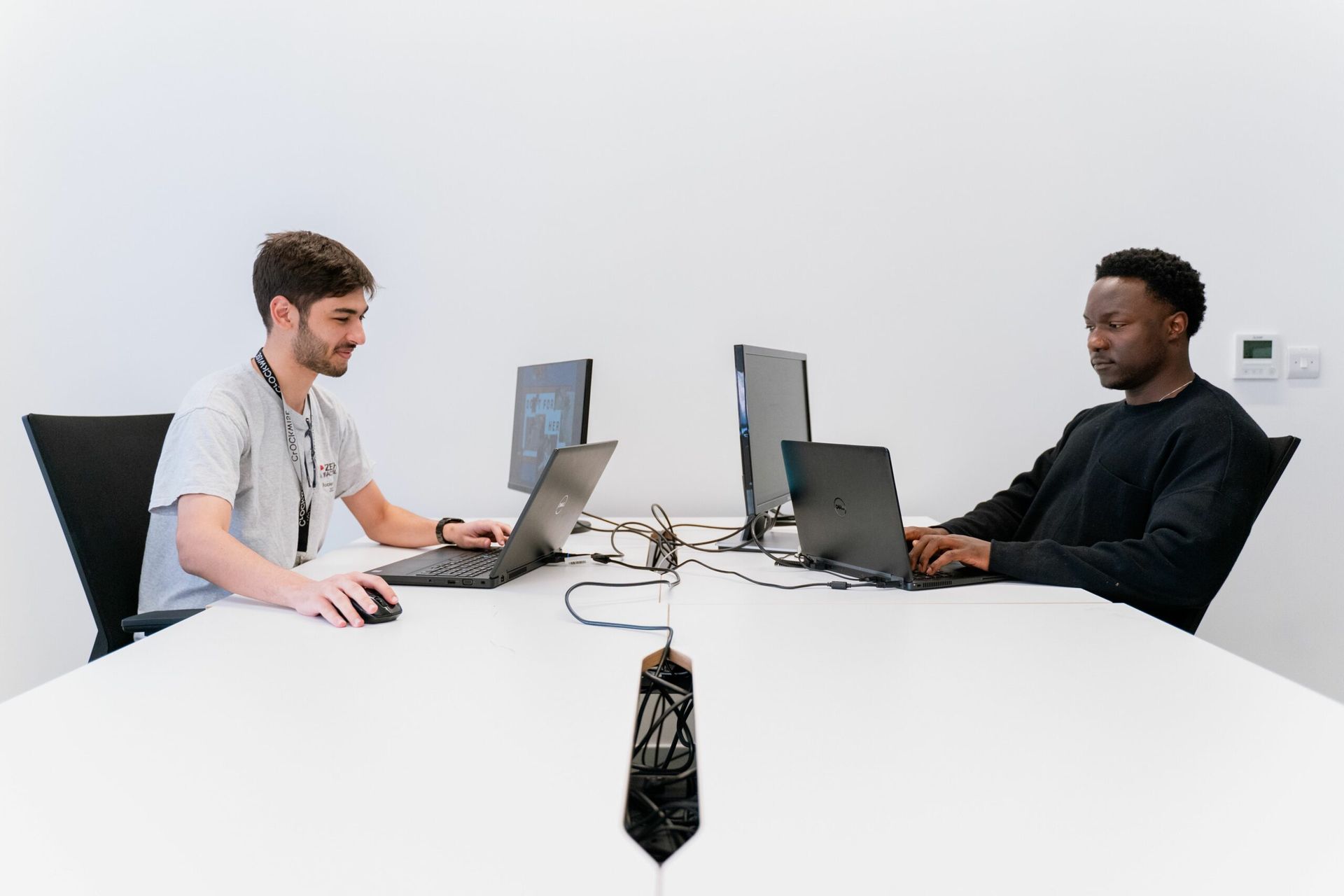 two people on laptops sitting at a desk