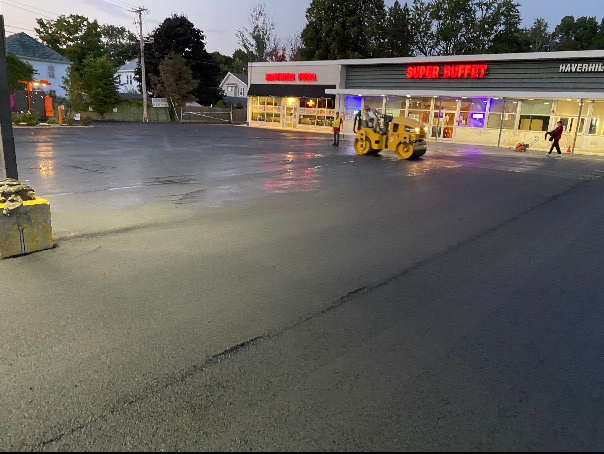 Orange traffic cone in a newly painted parking space, with yellow lines on asphalt, houses in the background.