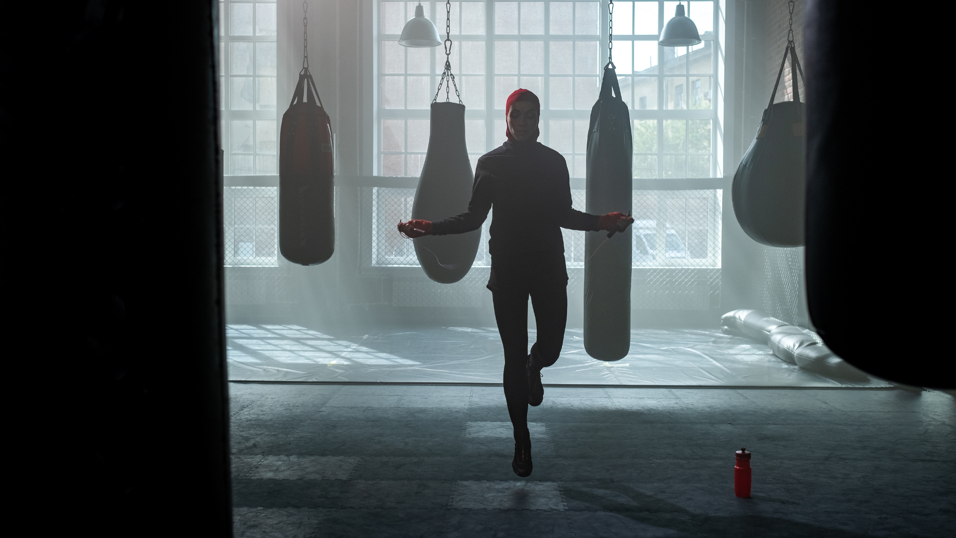 A man is jumping a jump rope in a boxing gym.