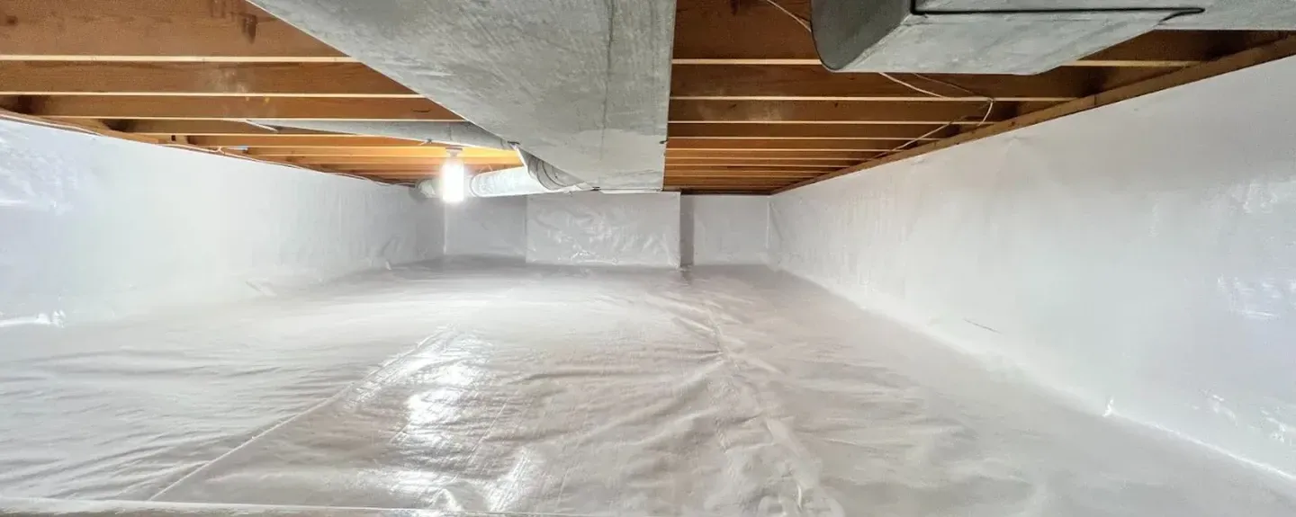 Basement with white plastic vapor barrier and exposed wooden ceiling joists