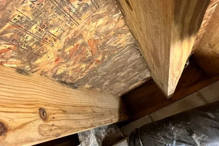 Close-up of wooden beams and plywood in an unfinished attic corner