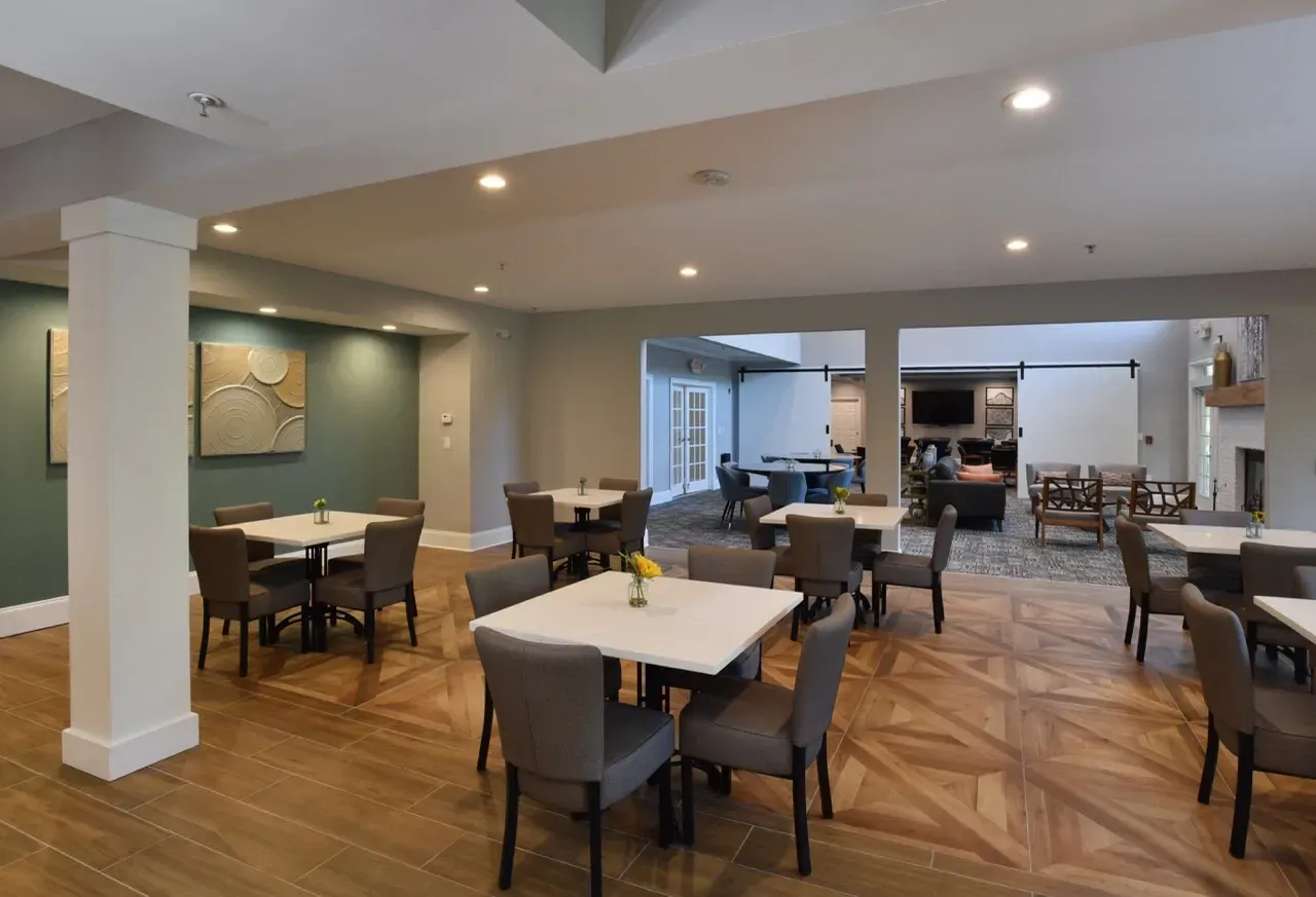 Indoor community lounge with tables, chairs, and a separate seating area.