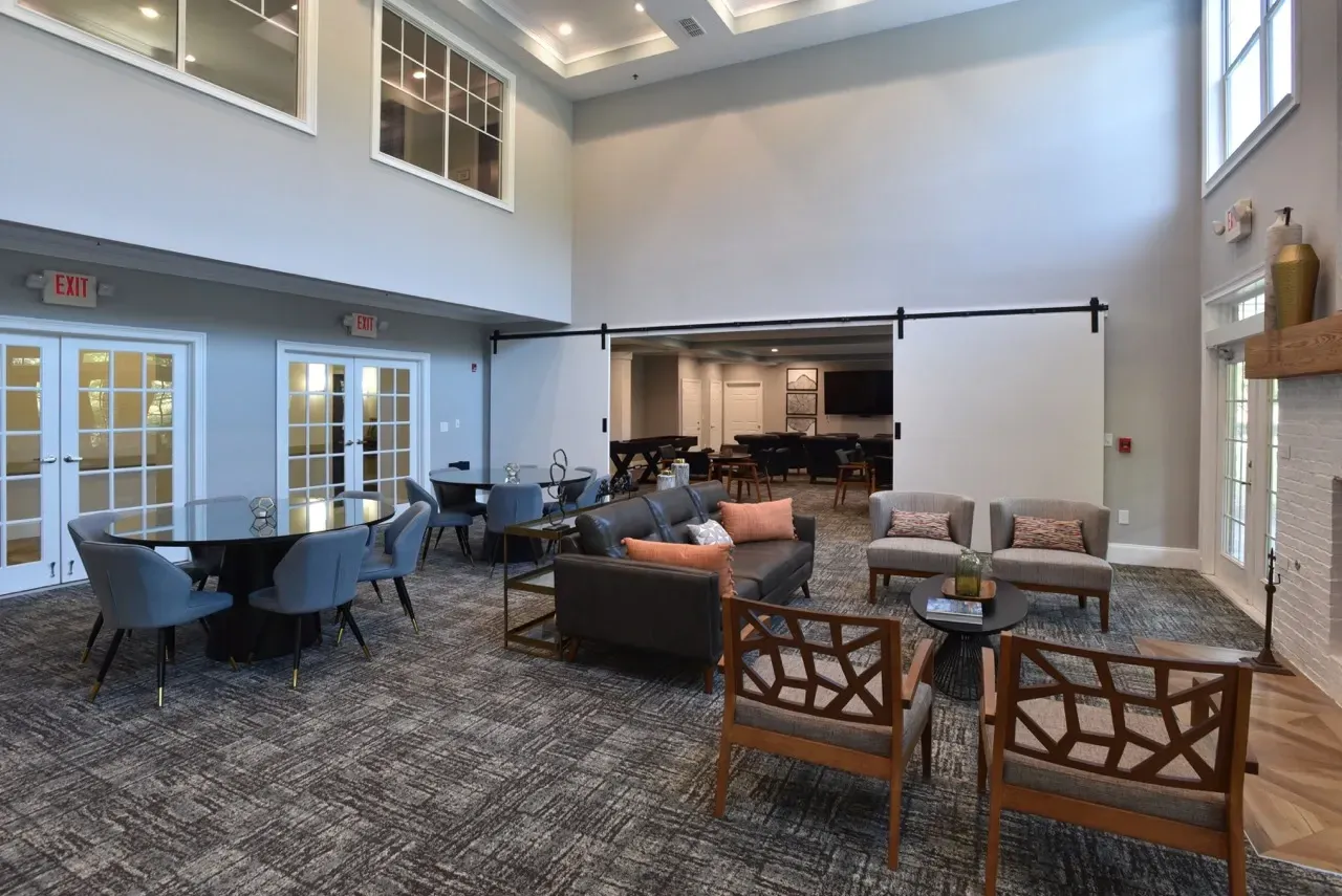 Open indoor community lounge with sofa seating, chairs, and round tables.