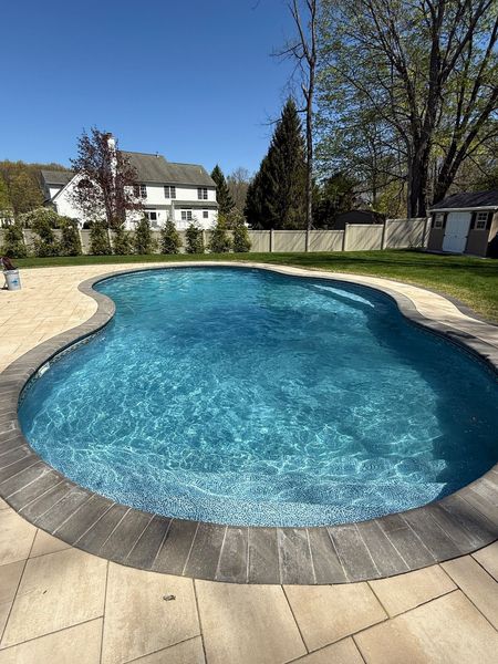 A large swimming pool in a backyard with a house in the background.