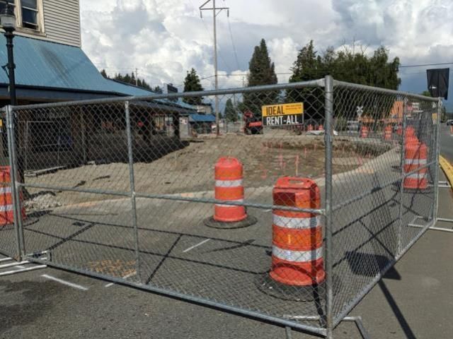A chain link fence surrounds a construction site with orange cones