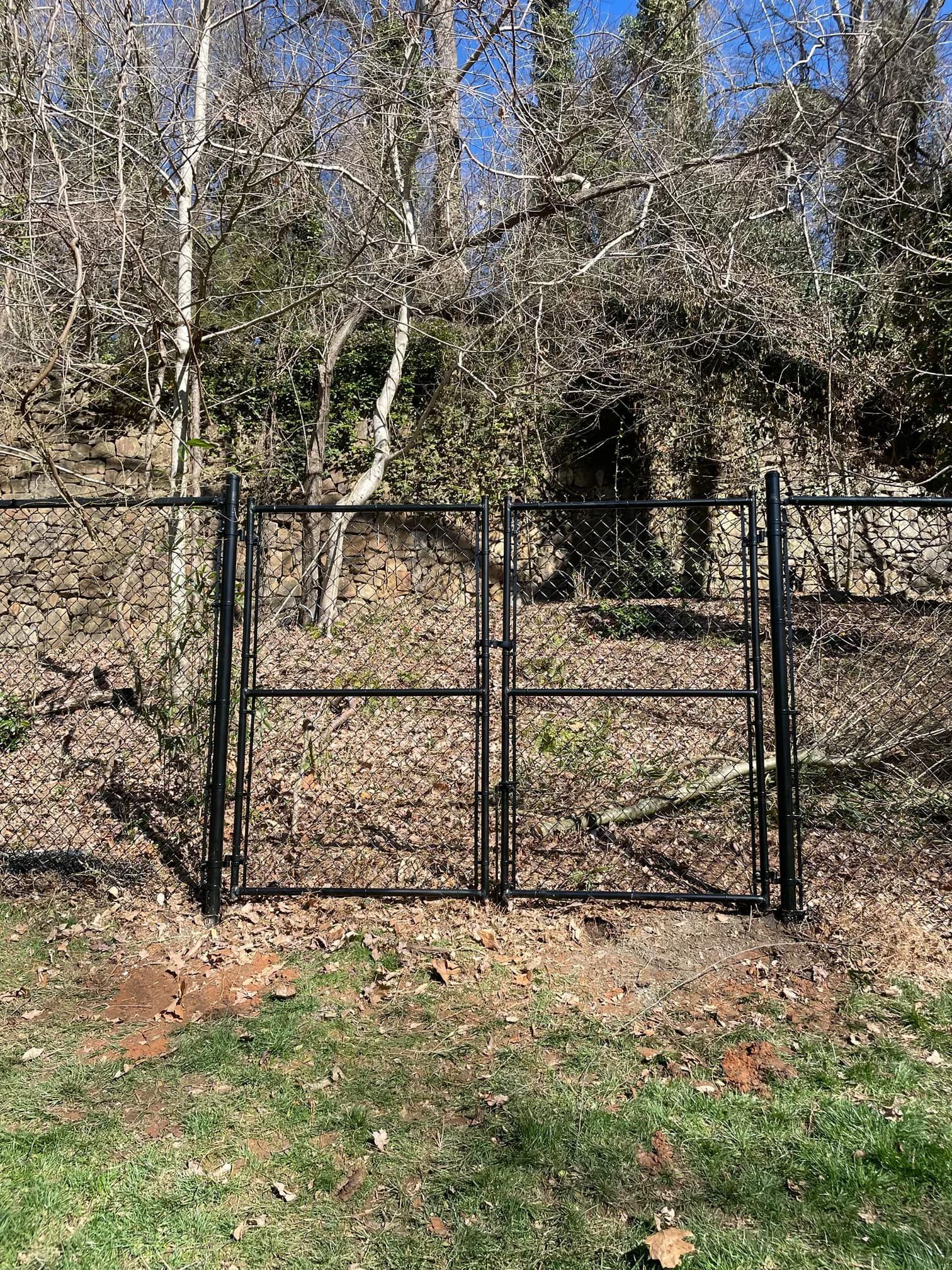 A black metal gate is sitting in the middle of a grassy field.