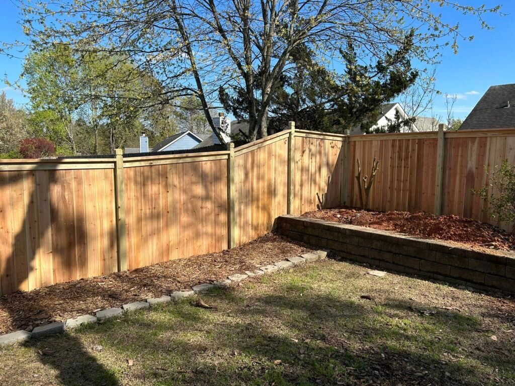 A wooden fence is in the backyard of a house.