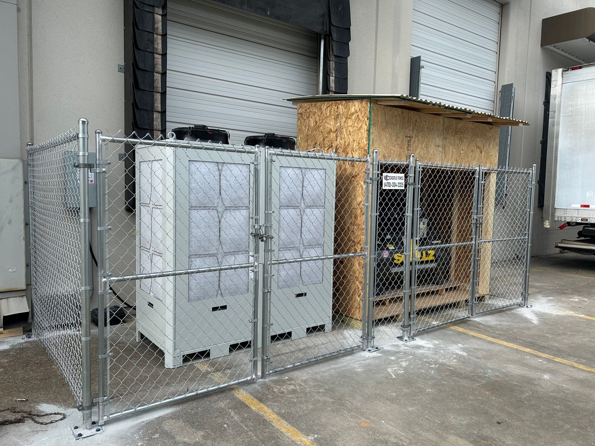 A chain link fence is surrounding a warehouse with containers in it.