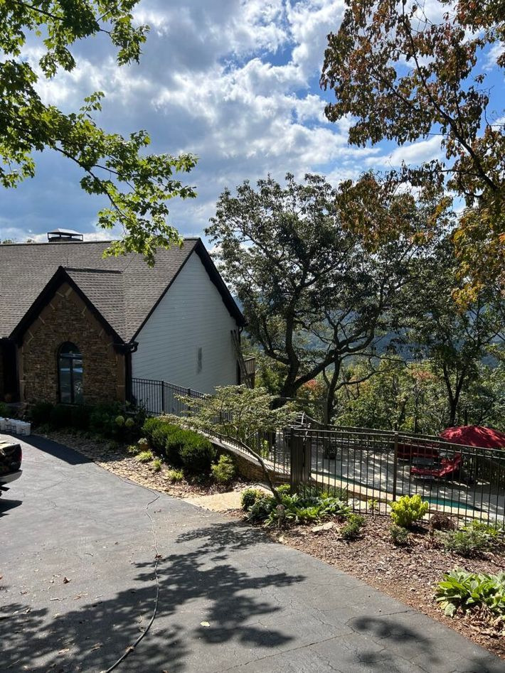 A driveway leading to a house with a pool in the background.