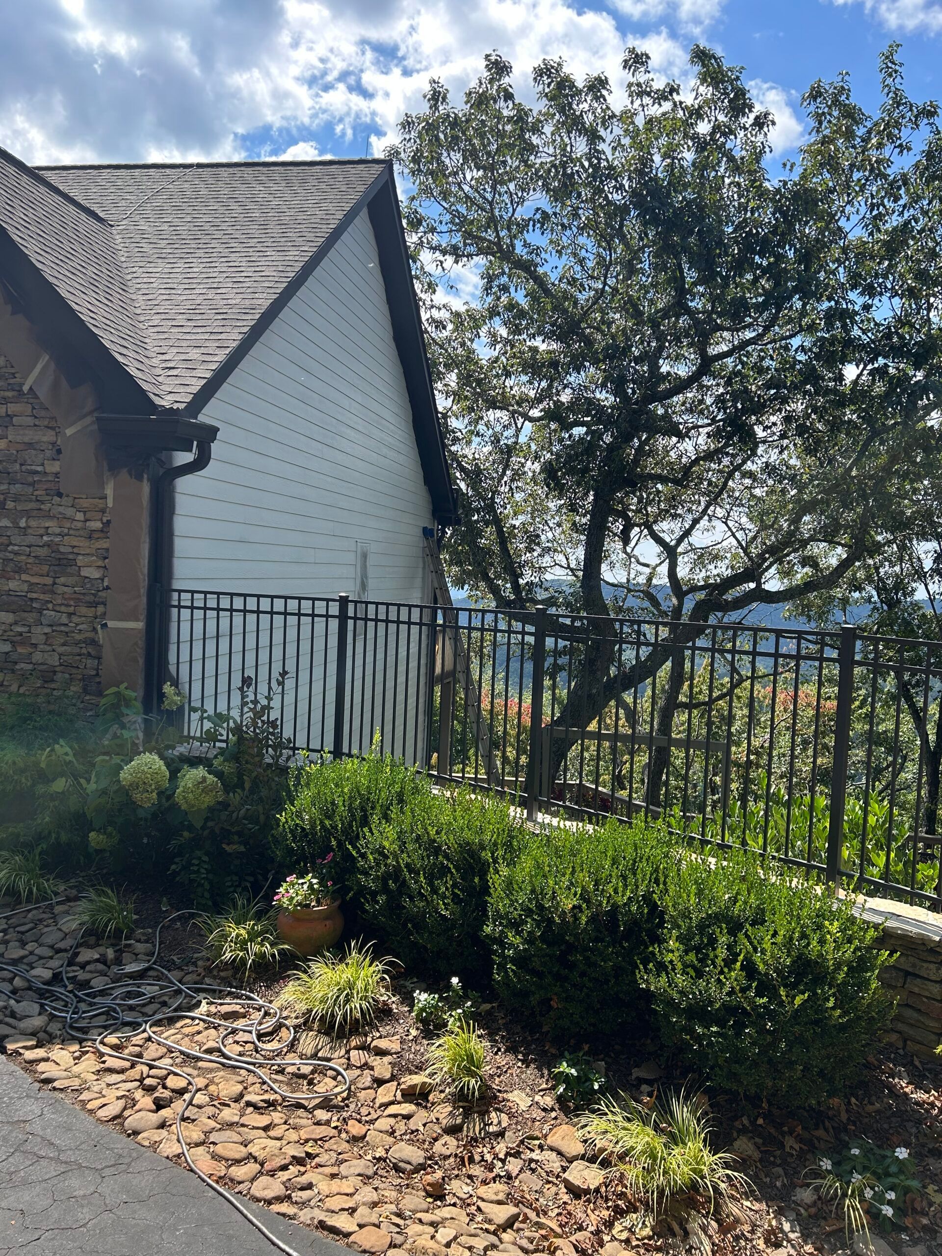A house with a fence and bushes in front of it