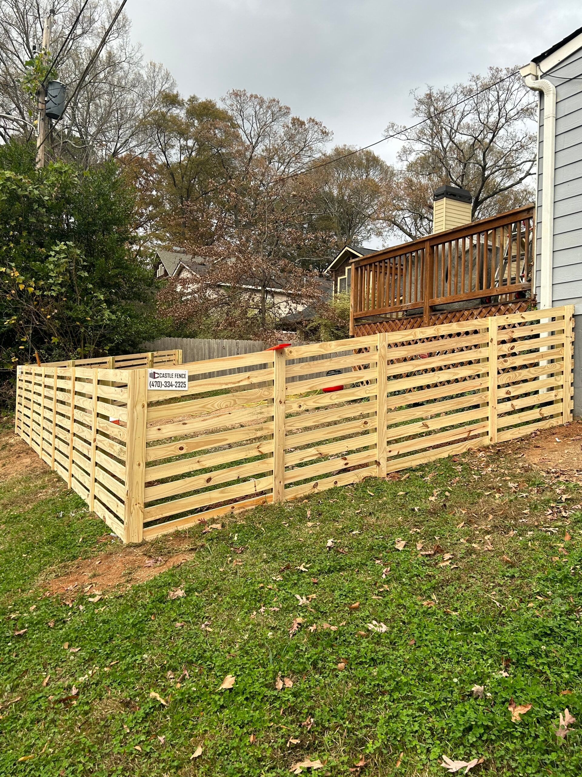A wooden fence is in the backyard of a house.