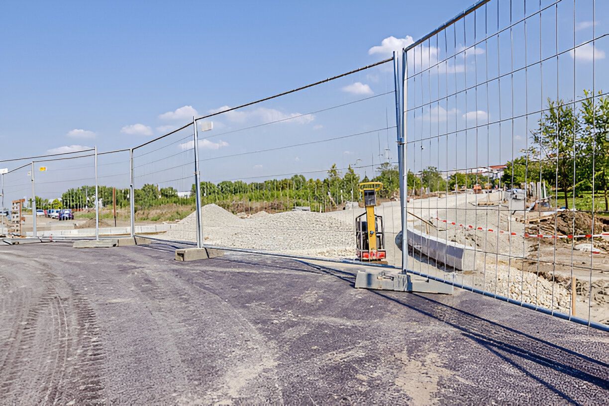 A fence is surrounding a construction site on a sunny day.