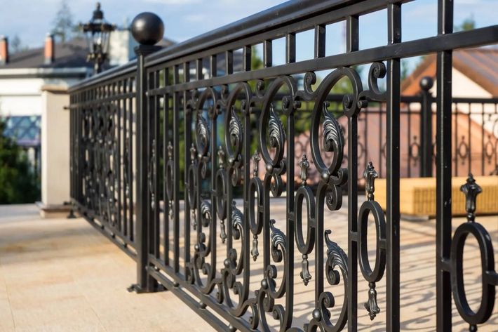 A close up of a wrought iron fence on a balcony.