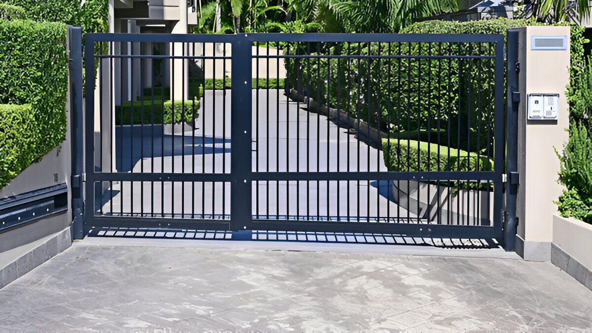 A black gate is open to a driveway in front of a house.
