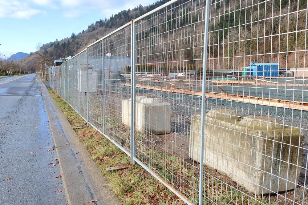 A metal fence surrounds a construction site next to a road.