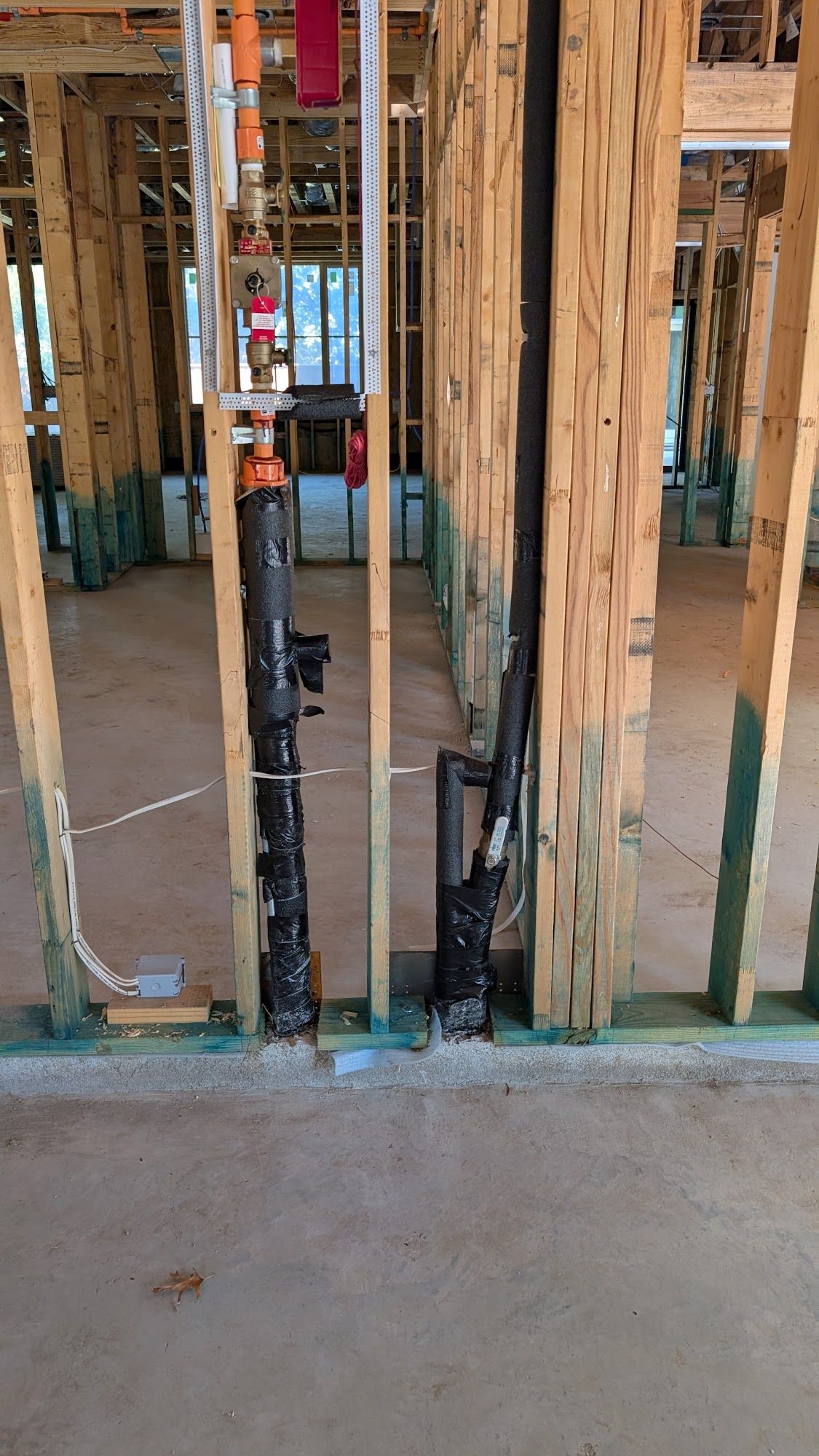 Framed walls with plumbing and pipes. Construction site, interior view.