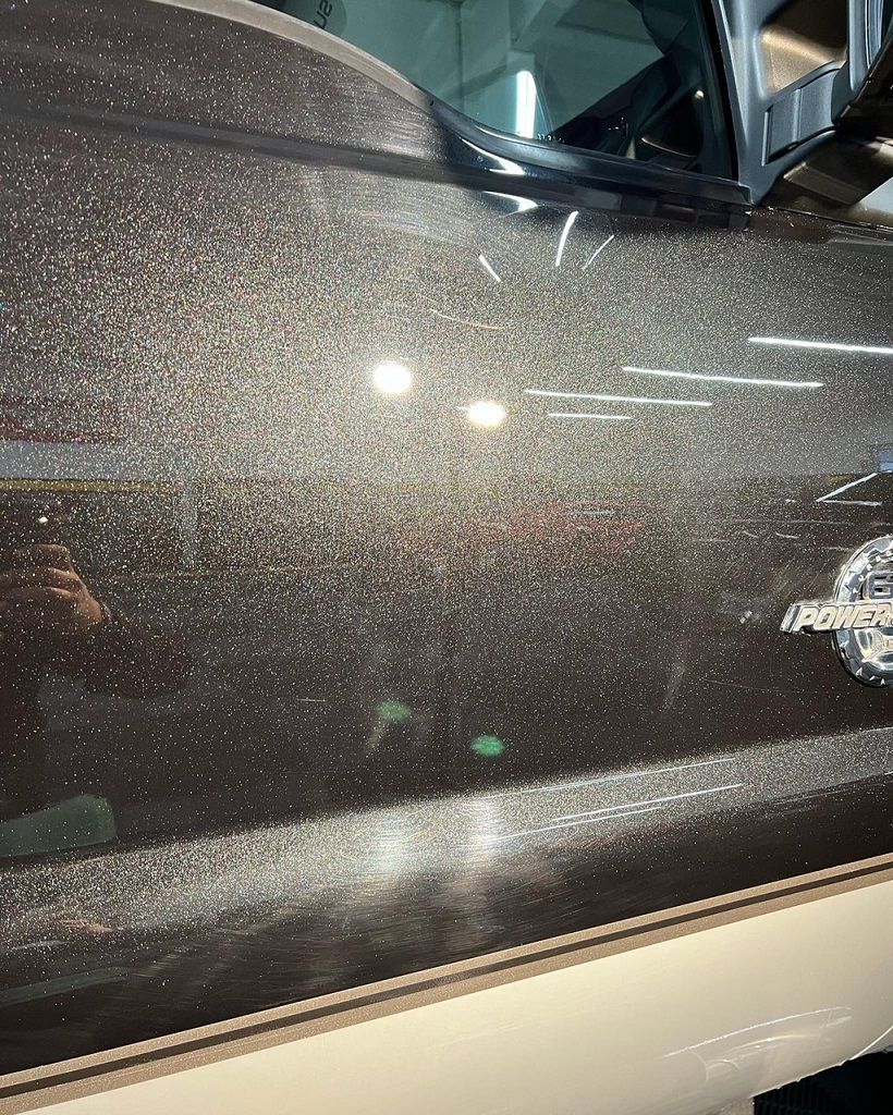 Dark vehicle door with sparkling metallic paint; a reflection is visible.