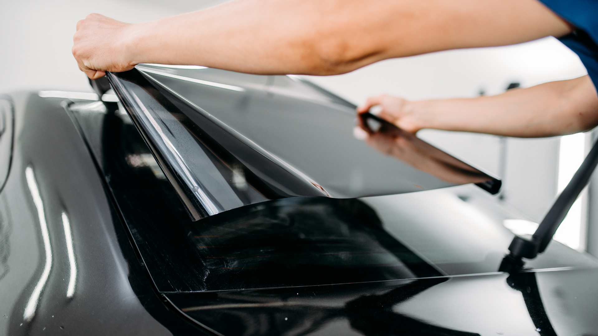 A person is applying tinted glass to a car window.
