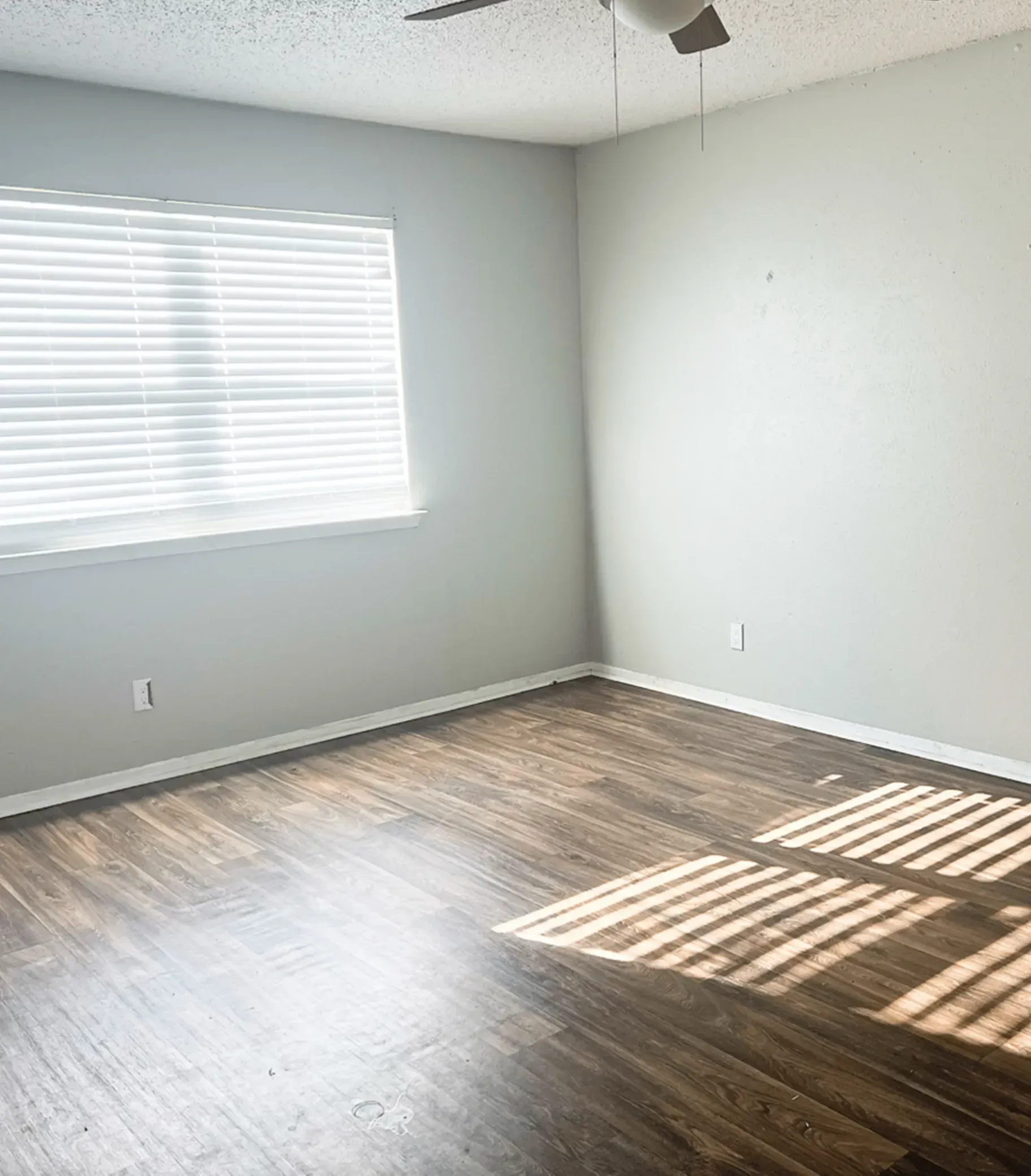 An empty room with hardwood floors and a ceiling fan.