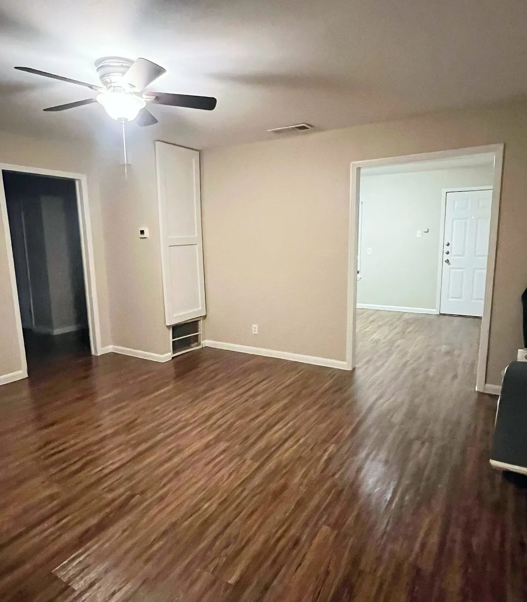 A living room with hardwood floors and a ceiling fan.