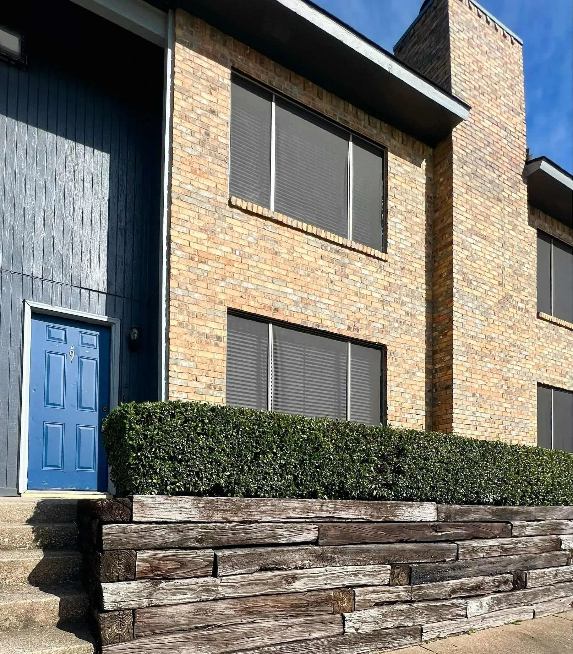 A brick building with a blue door and a stone wall