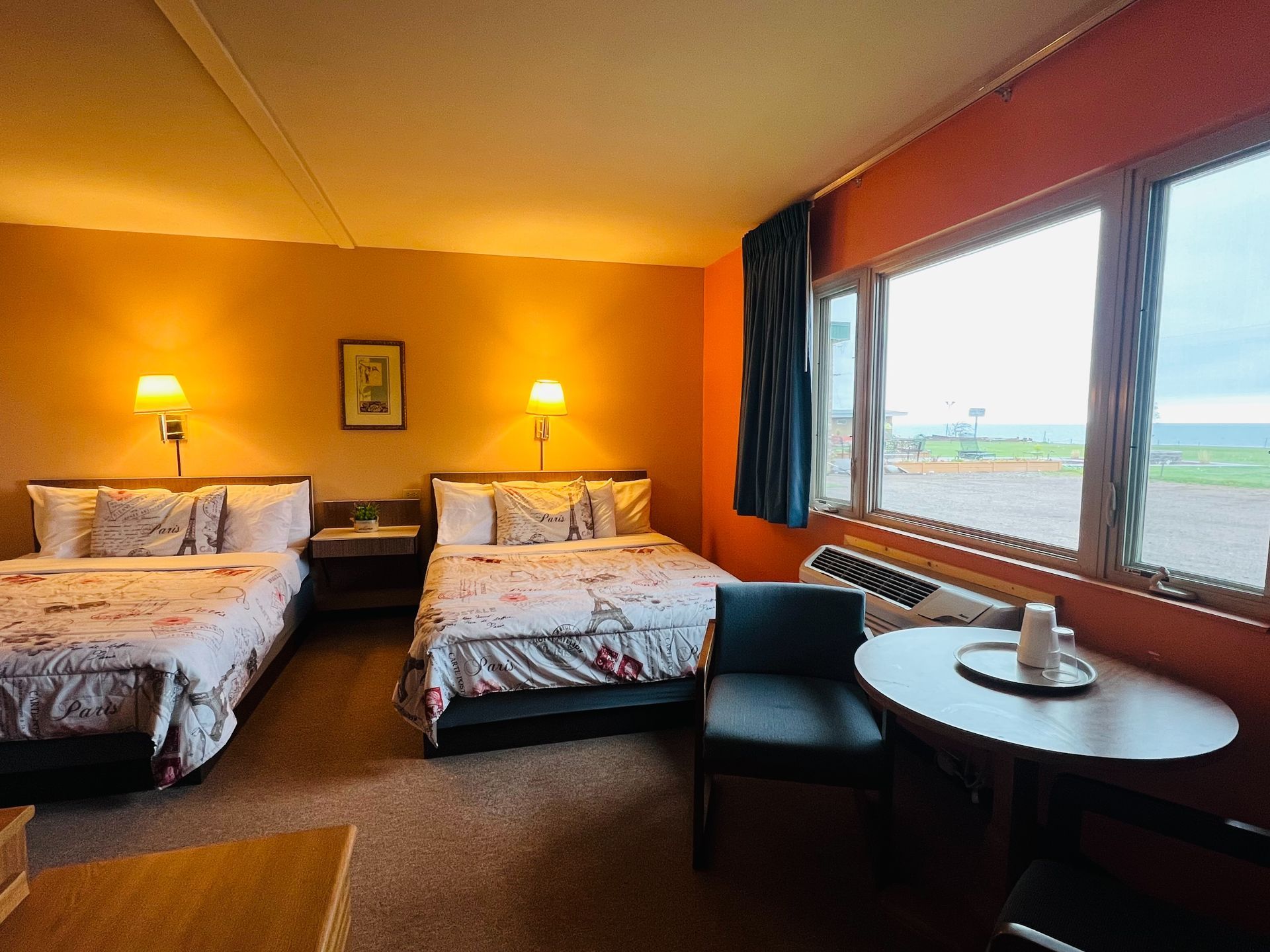 A hotel room with two beds , a chair and a table.